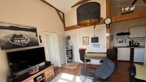 A cozy living room with a flat-screen TV, wooden entertainment unit, and a fireplace. - Apartment near the beach in the city center  (Rerik)