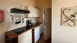 A compact kitchen with white cabinets, a black countertop, and a wooden ceiling. - Apartment near the beach in the city center  (Rerik)