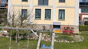 A two-story house with a balcony, a swing set, and a garden. - Apartment near the beach in the city center  (Rerik)