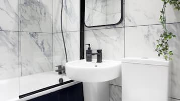 A bathroom with a white sink, a black faucet, a white toilet, and a black bathtub.