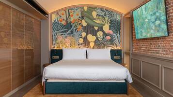 A bedroom with a large bed, a headboard with a mural, a brick wall, and a painting on the wall.