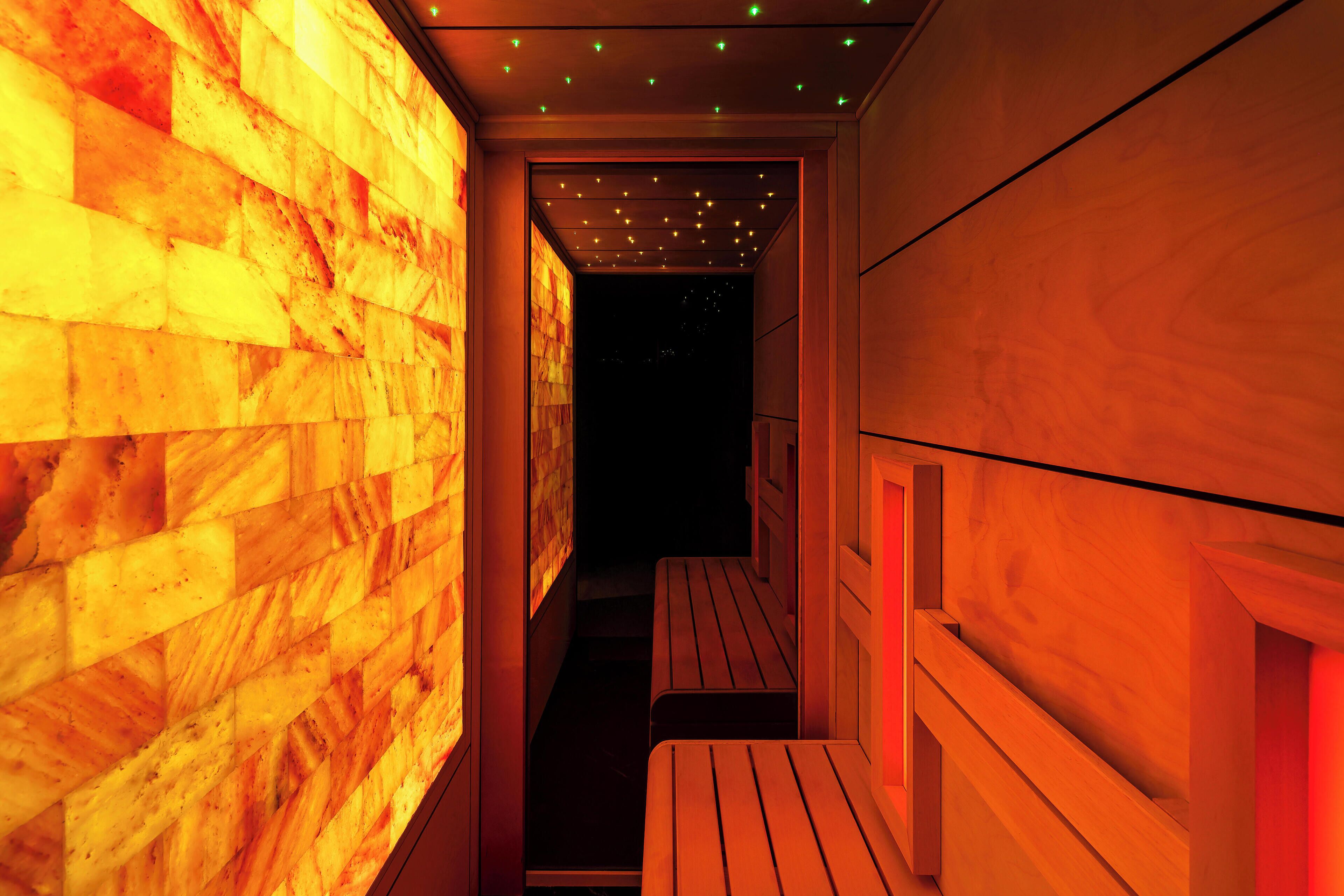 A narrow hallway with wooden benches and a wall with a warm, glowing pattern.