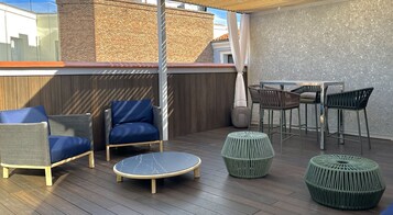 Una terrazza esterna con pavimento in legno, un tavolo rotondo e diverse sedie.