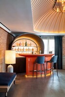 Eine Bar mit einer gebogenen Holztheke, zwei Barhocker und einer ausstellbaren Spirituosenflasche.
