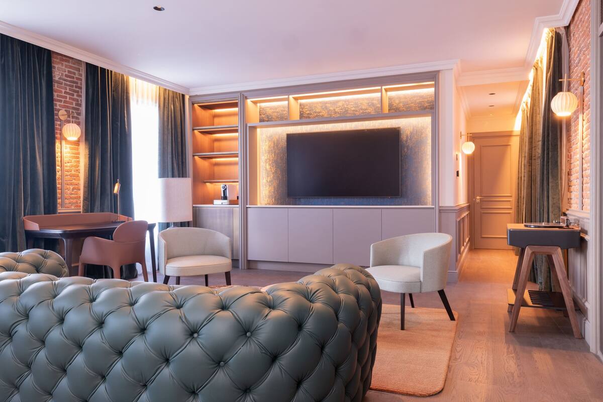A modern living room with a large flat-screen TV, comfortable seating, a dining area, and a kitchen.