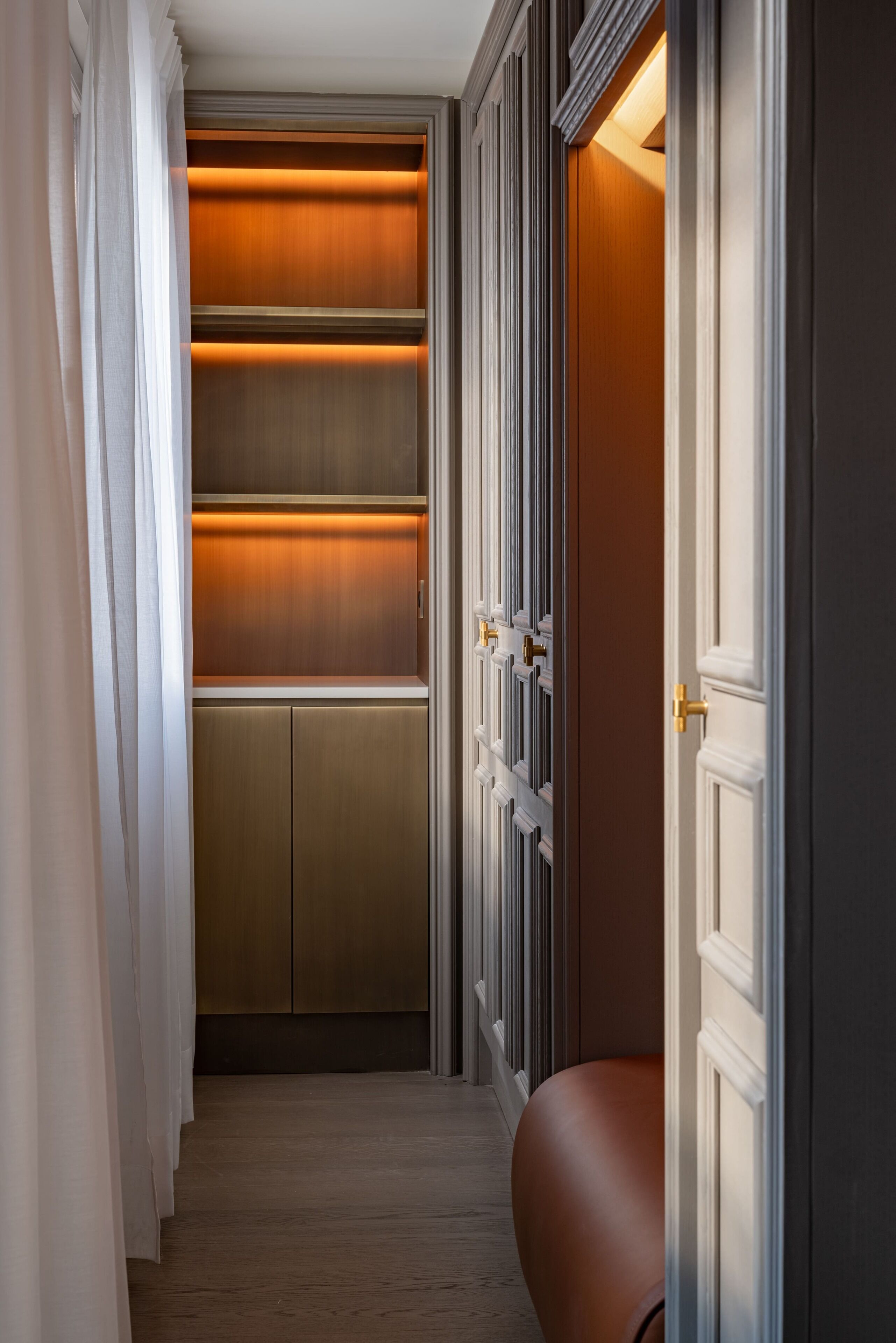 A narrow hallway with a wooden floor, a built-in closet with sliding doors, and a door with a brass handle.