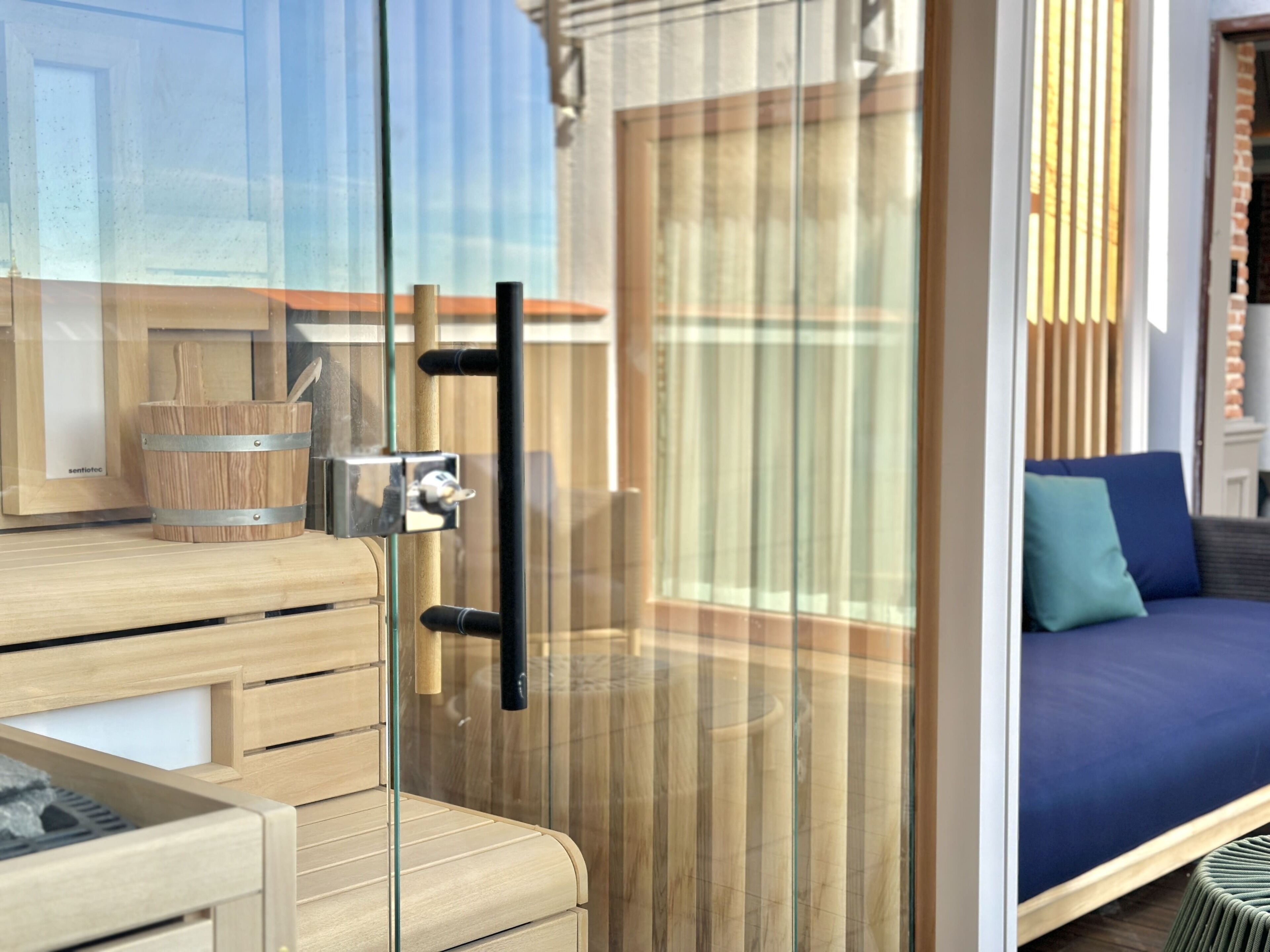 A modern room with a glass door, wooden furniture, and a blue sofa.