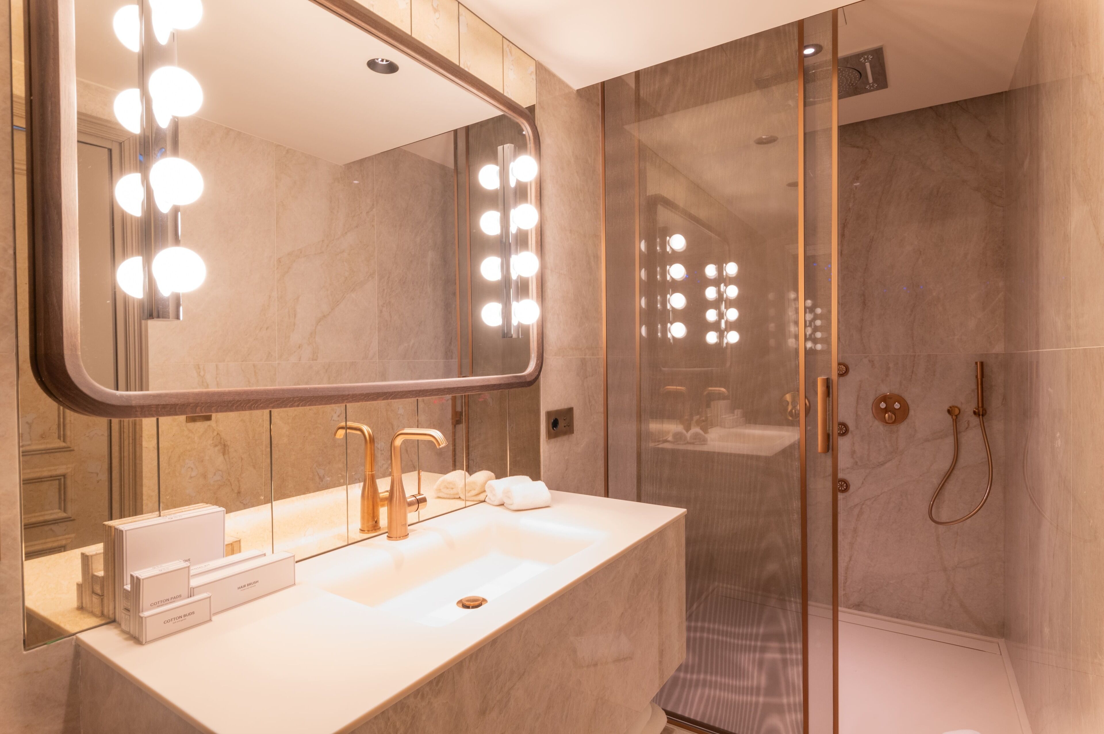 Un baño moderno con un espejo grande, tocador y cabina de ducha.