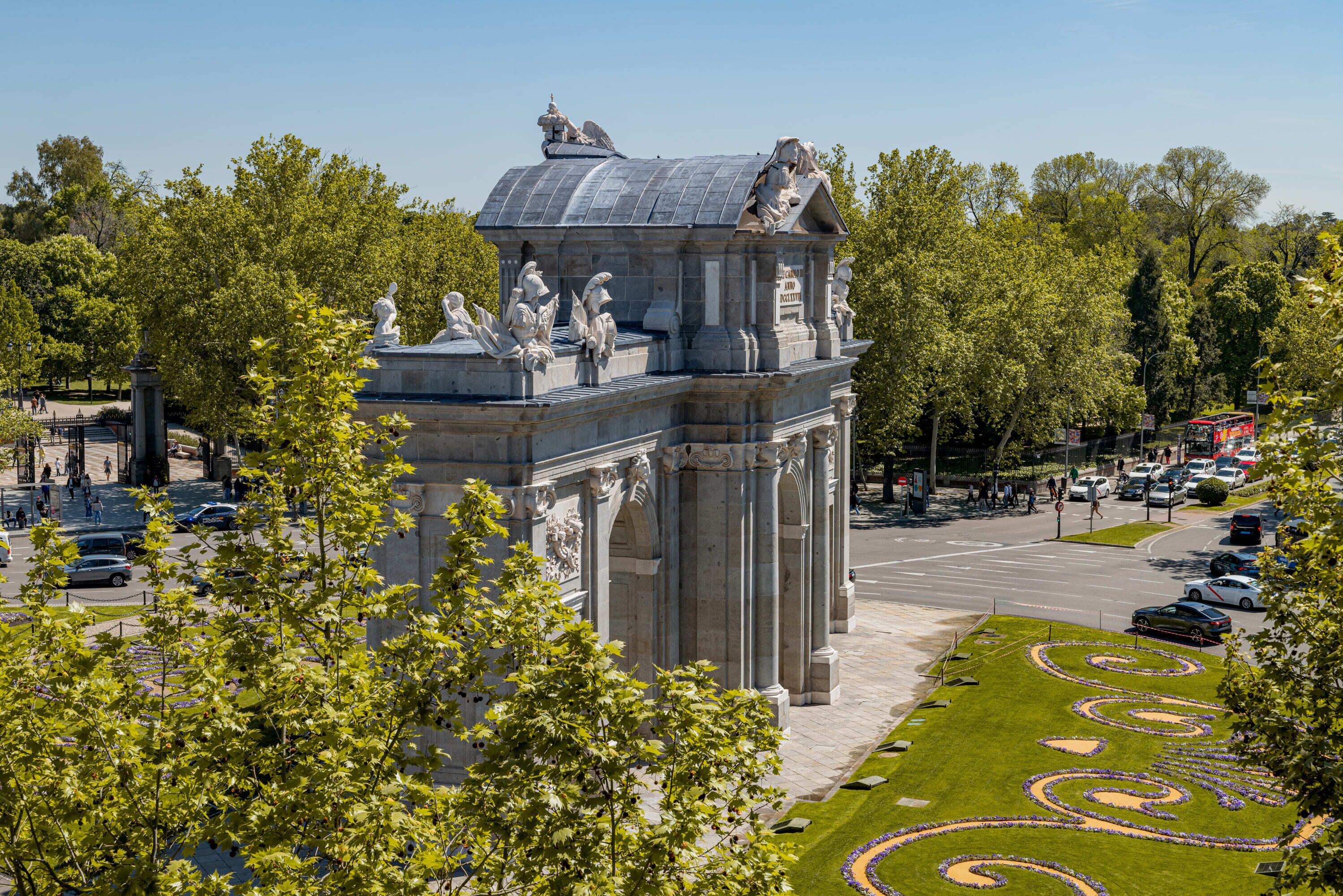 Un edificio grande y ornamentado de arquitectura clásica, rodeado por un césped cuidado y árboles.
