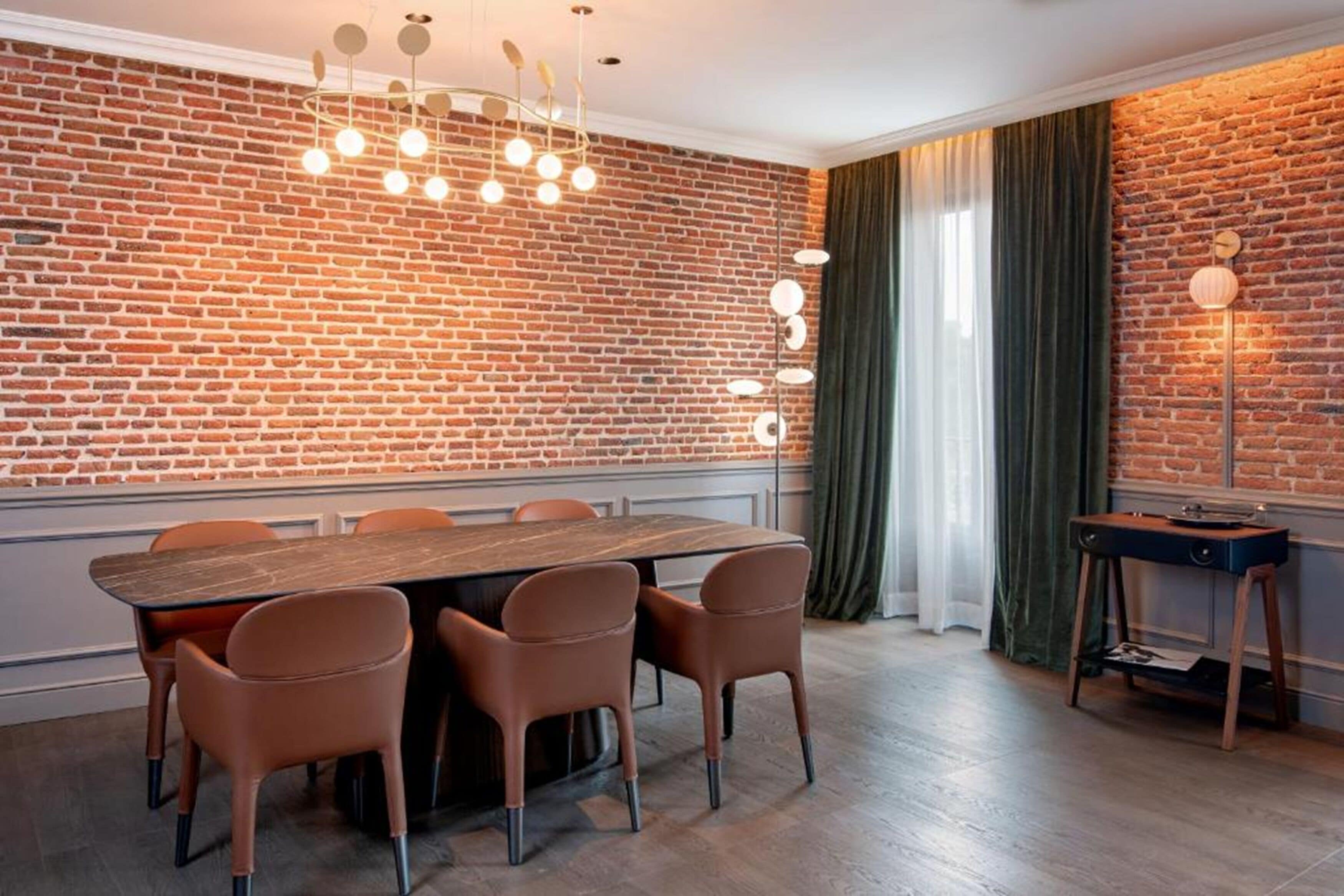Een eetgedeelte met een bakstenen muur, een houten tafel en zes stoelen.
