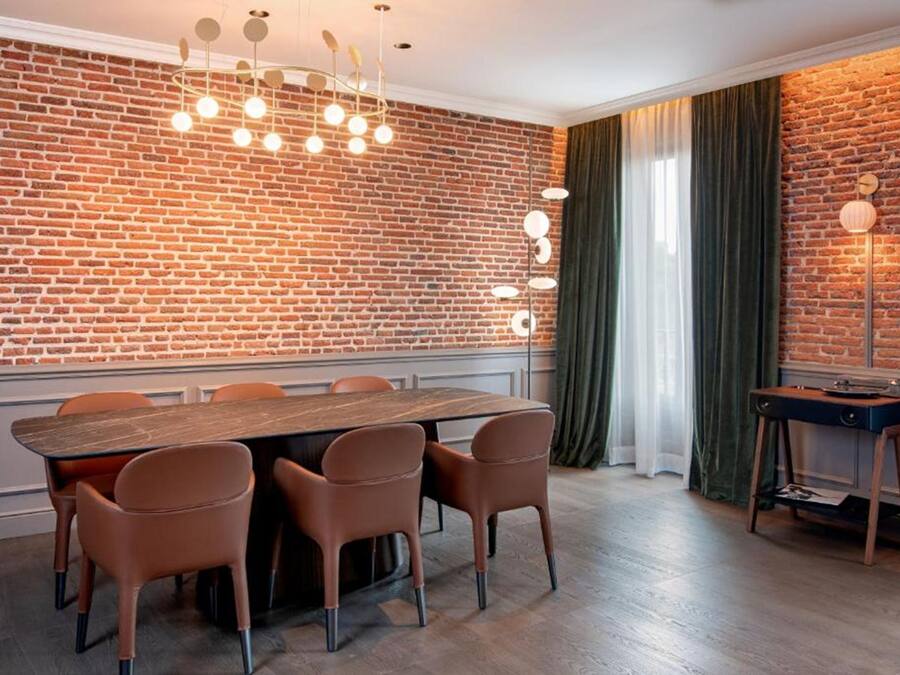 Een eetgedeelte met een bakstenen muur, een houten tafel en zes stoelen.