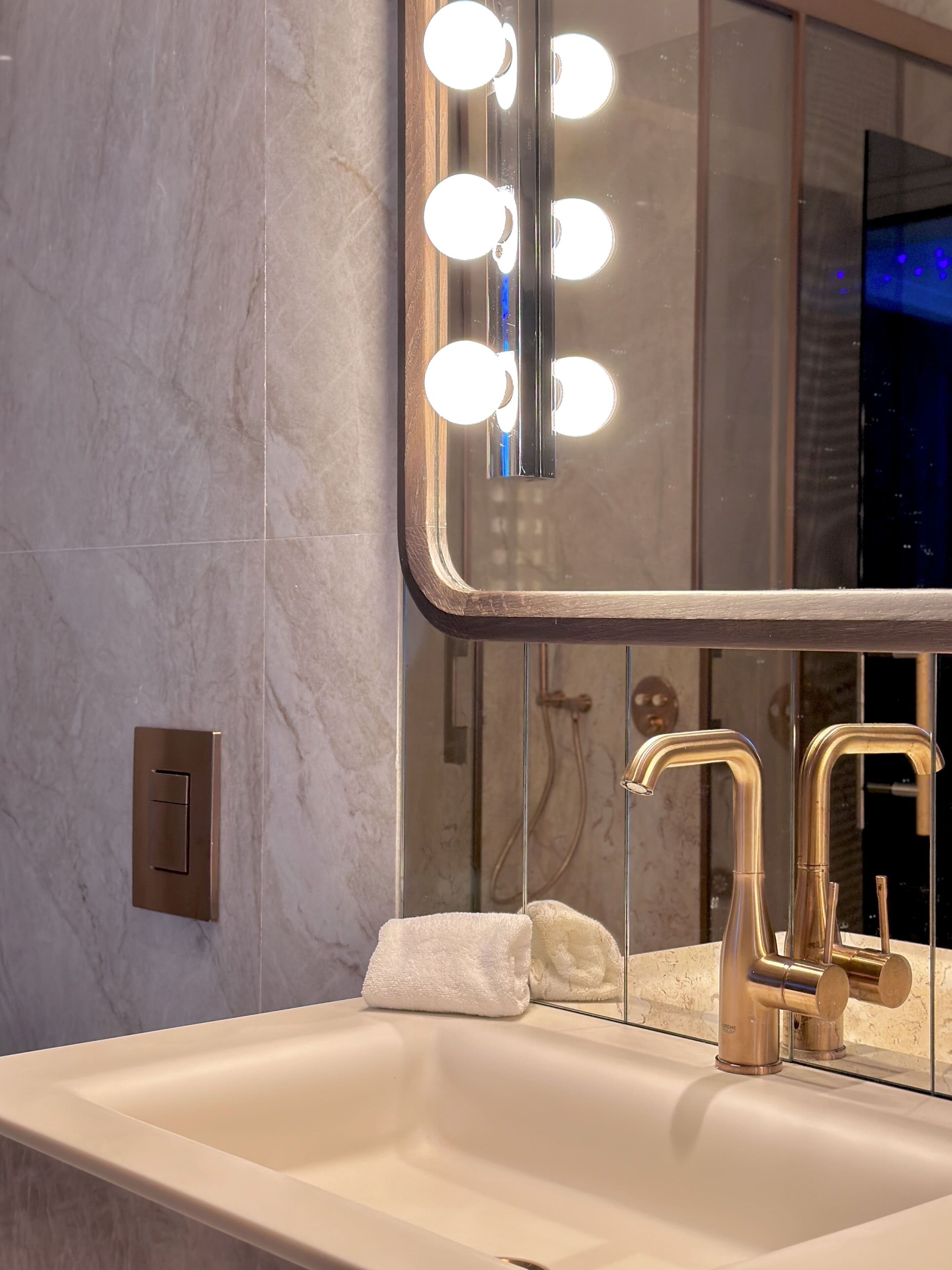 A bathroom with a large mirror, vanity, and dual sinks.