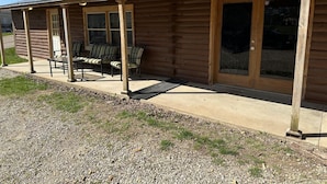 Eine Blockhütte mit Veranda, Gartenmöbeln und einem überdachten Eingangsbereich.