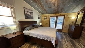 Ein Schlafzimmer mit Holzboden, einem Bett mit Kopfteil, einem Schminktisch und einem Fenster mit Jalousien.