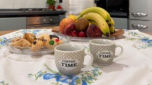 Eine Küche mit einem für das Frühstück gedeckten Tisch, einschließlich Früchten, Gebäck und Kaffeetassen.