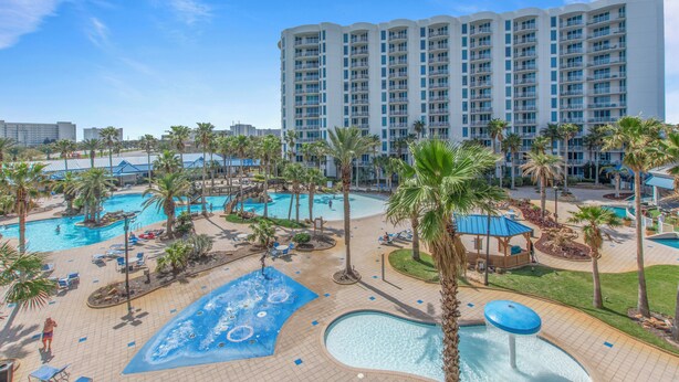 A hotel with multiple swimming pools, palm trees, and a large building in the background. - 🌴The Palms of Destin 1411 - The Pretty Palm | Easy Beach Access | Great Views🌴 (Destin)