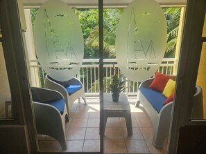 Un balcon agrémenté de meubles en osier, d’une petite table et d’une plante en pot.