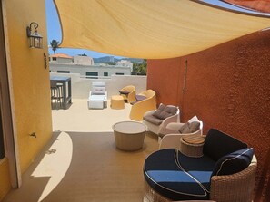 Un espacio al aire libre con mesas y sillas de lounge, una sección cubierta y una mesa redonda.