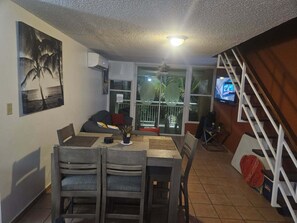 A dining area with a table, chairs, and a TV on the wall.