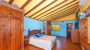 A bedroom with a bed, wooden wardrobe, and a small table with a lamp. - Villa Casa Tania by Villa Plus (Frigiliana)