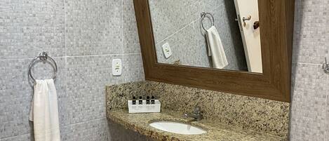 Un baño con lavamanos de encimera de granito, un armario de medicinas de madera y un espejo.