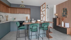 A modern kitchen with a central island, bar stools, and a wooden accent wall. - Apartment for 4, center and seaside (Saint-Brevin-les-Pins)