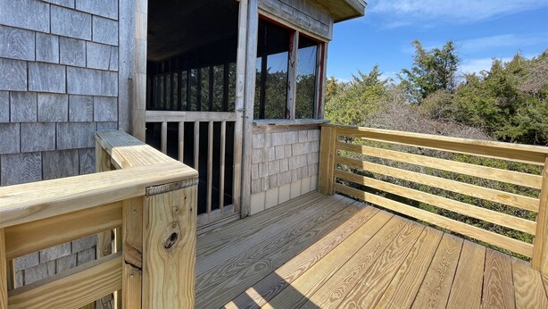 A wooden deck with a railing, a wooden door, and a window.