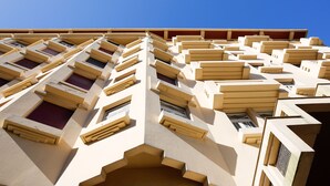 Un edificio de varios pisos con un diseño arquitectónico único, que cuenta con numerosos balcones y ventanas.