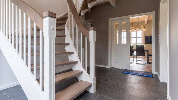 A staircase with wooden steps and white railings leading to a room with a dining area. - Doppelhaushälfte in Karolinenkoog (Karolinenkoog)