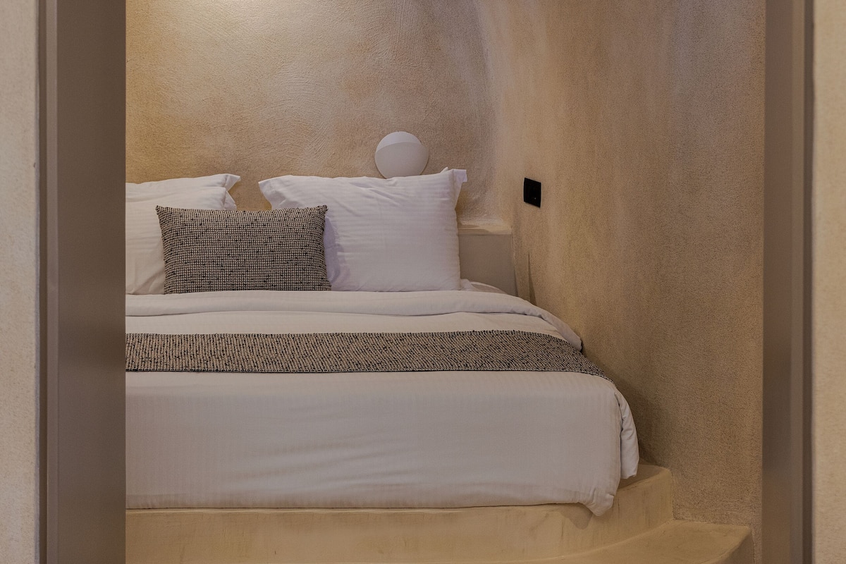 Une chambre confortable à l’ambiance chaleureuse, avec un lit, des oreillers et une couverture.