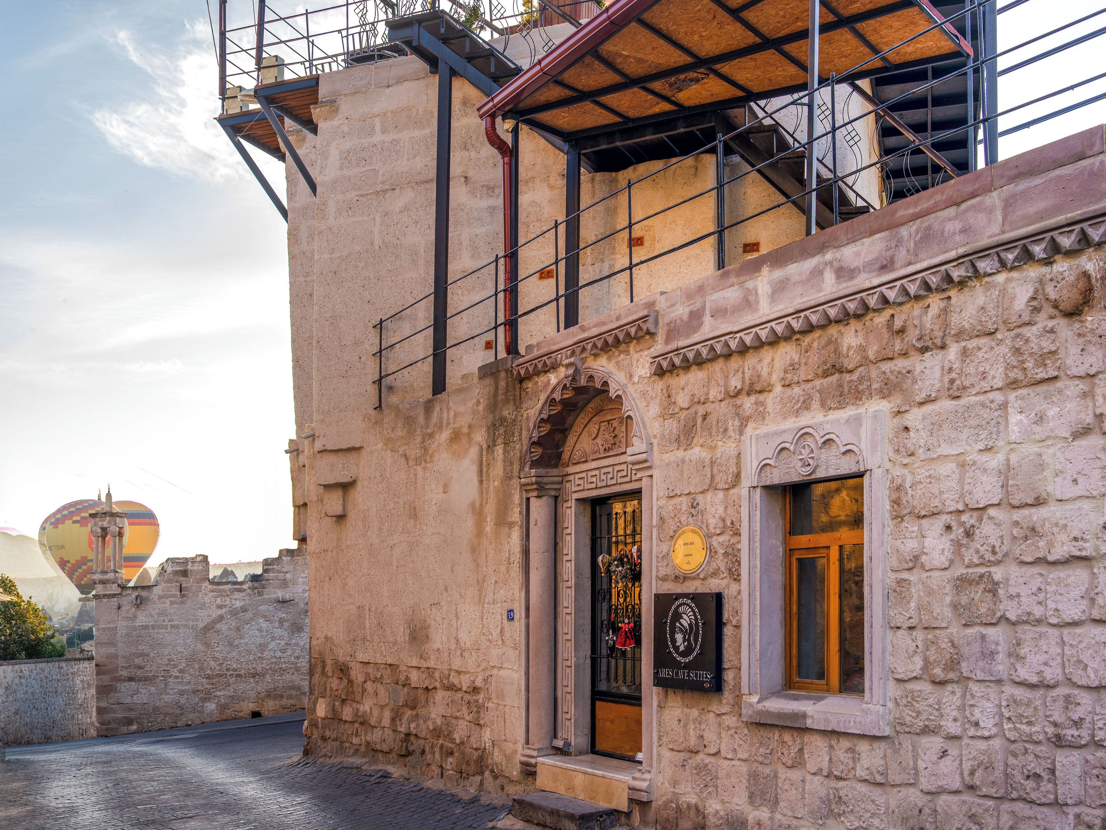 A historic stone building with a traditional arched entrance, a plaque, and a staircase leading to an upper level.