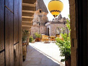 Un área de estar al aire libre con paredes de piedra y un globo aerostático al fondo.