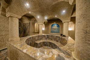 A luxurious spa with a marble jacuzzi, stone walls, and a mural of a horse. - Ares Cave Suites (Nevsehir)