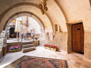 An interior with stone arches, a wooden door, a staircase, and a dining area with tables and chairs. - Ares Cave Suites (Nevsehir)