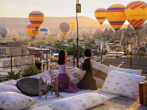 A rooftop with a view of a cityscape and hot air balloons in the distance. - Ares Cave Suites (Nevsehir)