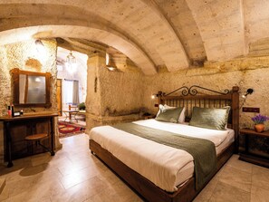 Quarto rústico com cama de madeira, espelho e parede de pedra.