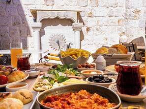A table set with various dishes, including bread, cheese, and a bowl of olives. - Ares Cave Suites (Nevsehir)