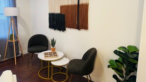 Une pièce moderne comprenant deux chaises, une petite table, un lampadaire et une décoration murale en macramé.