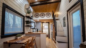 A modern kitchen with wooden accents, a central island, and a view into the dining area.