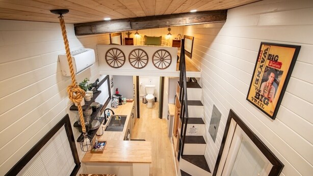 A narrow, multi-level interior with a kitchen area, a staircase, and a dining area.