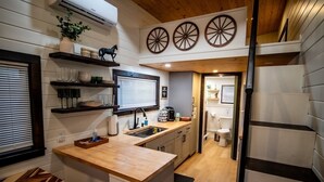 A modern kitchen with wooden countertops, a built-in sink, and a window with blinds.