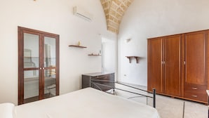 Ein Schlafzimmer mit Bett, Kleiderschrank, Schreibtisch und Spiegel.