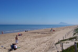 A beach with people sunbathing and walking along the shore.