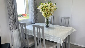A dining area with a table, chairs, and a vase of flowers. - Modern Homely Chalet in Tuxford (Newark)
