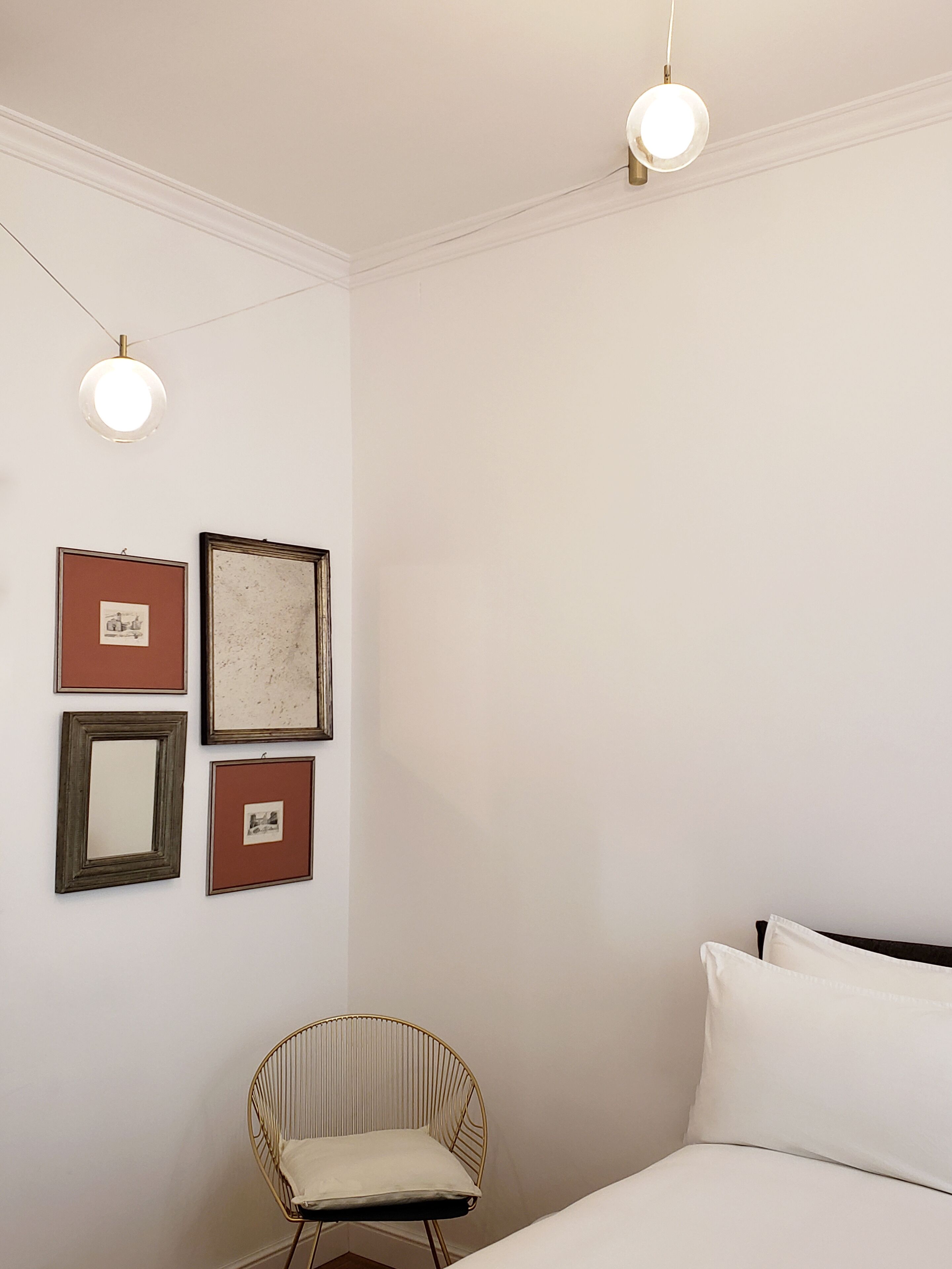 A bedroom with a bed, a chair, and wall-mounted lights.