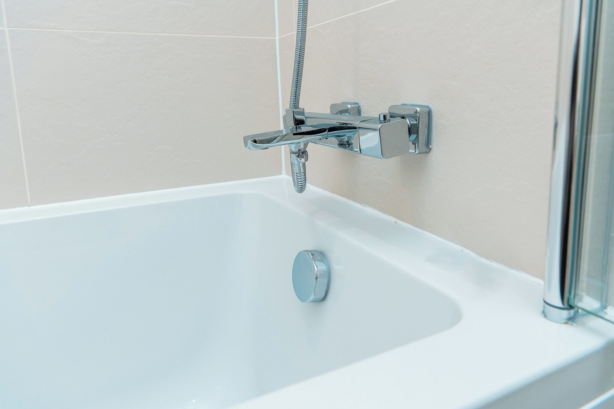 Un baño moderno con una bañera blanca, accesorios de cromo y una cabina de ducha de vidrio.