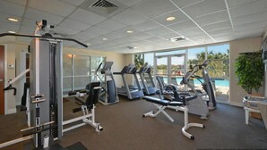 A gym with various exercise equipment, large windows, and a view of a pool. - Terrace @ Pelican Beach Resort 307b * Hotel accommodation * Salt Water Vacations (Destin)