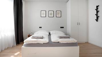 Quarto moderno com cama de casal, guarda-roupa e três quadros na parede.