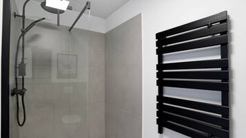 A modern bathroom with a glass shower enclosure, a black towel rack, and a visible toilet.