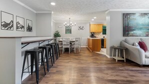 A modern kitchen with a dining area, wooden flooring, and a bar counter. - Lakeside Paradise Escape/Jet Ski & Kayak Adventure (Dandridge)